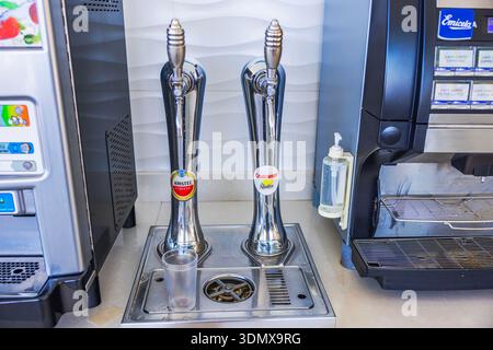 Nahaufnahme der Bierzapfen mit Amstel- und Cruzcampo-Etiketten, die an der Bar neben der Kaffeemaschine in der Hotelbar angebracht sind. Gran Canaria. Spanien. Stockfoto