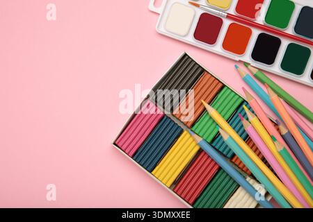 Buntstifte, Plastilin und Aquarellfarben auf rosa Hintergrund. Draufsicht Stockfoto