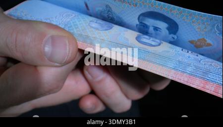 Eine Banknote in der Hand mit Gelddesign und Porträt des Führers in schwacher Beleuchtung Stockfoto