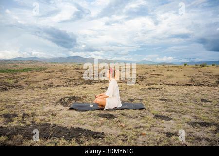 Ein ruhiger Moment der Meditation in der weitläufigen Tatacoa-Wüste, Kolumbien, in dem die Essenz von Achtsamkeit und Yoga-Praxis in einer ruhigen Natur festgehalten wird Stockfoto