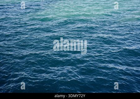 Ein riesiges tiefblaues Meer mit sanften Wellen an der Oberfläche, die eine ruhige und beruhigende Szene schaffen. Das Wasser reflektiert das Licht und verleiht so ein Gefühl von t Stockfoto