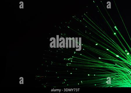 Abstraktes Bild grüner Neonfaser-Lampen vor schwarzem Hintergrund. Die leuchtenden Stränge erzeugen komplizierte Muster, die futuristisch und gravierend wirken Stockfoto