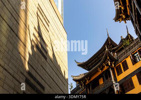 Ein beeindruckendes Bild in Chongqing, wo die traditionelle chinesische Architektur harmonisch mit einem modernen Gebäude kontrastiert. Die Szene zeigt Kulturhisto Stockfoto