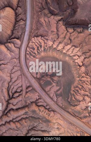 Luftbild mit den einzigartigen, strukturierten Mustern der trockenen Landschaft im Altiplano Andino, Argentinien. Die kurvenreiche, unbefestigte Straße sorgt für Kontrast Stockfoto