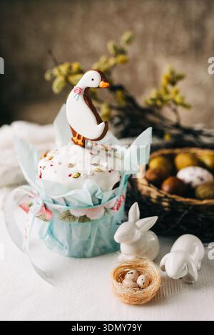 Festliche Osterkuchen mit einer entzückenden Entenauflage, umgeben von Porzellan-Hasen-Figuren. Ein entzückendes Herzstück, das den Frühling feiert Stockfoto