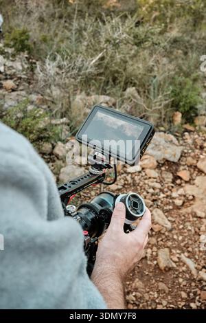 Videofilmer, der professionelle Kamera mit externem Monitor in der Natur bedient Stockfoto