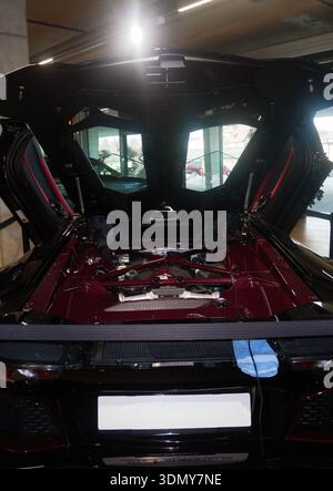 Der luxuriöse Sportwagen mit offener Motorhaube zeigt detaillierte Motorkomponenten und moderne Designmerkmale in einem hellen Ausstellungsraum Stockfoto