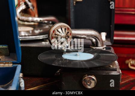 Nahaufnahme eines antiken Grammophons, das eine Schallplatte spielt, ein hinreißender Tonarm aus Metall und Retro-Design bei warmem Innenlicht Stockfoto