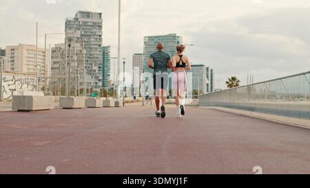 Panoramablick auf das Meer, junge aktive Paare, die zusammen am Strand joggen, Rückblick Stockfoto