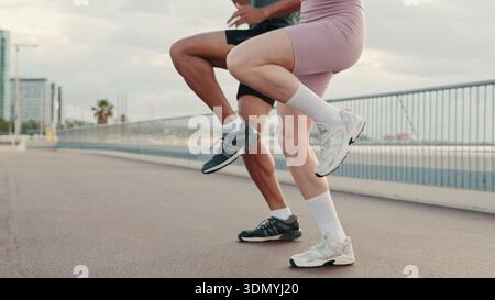Nahaufnahme eines multiethnischen Mannes und einer Frau, die Beine warm machen, bevor sie am Meer laufen, Sneaker-Fuß-Fokus Stockfoto