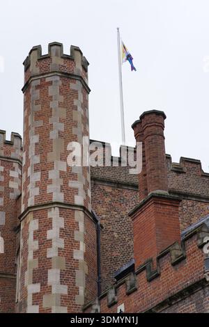 Der Backsteinturm mit Zinnen und die Schornsteine eines historischen Cambridge College mit der Flagge, die an einem grau bewölkten Tag fliegt. Cambridge, England Stockfoto