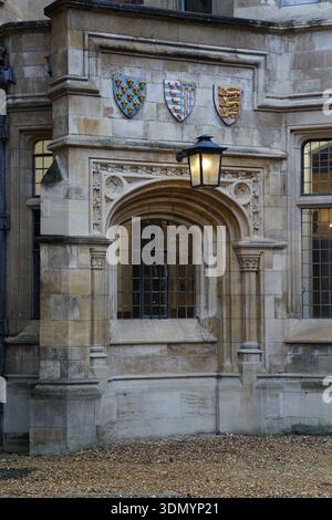 Reich verzierter Steineingang mit drei heraldischen Schilden und gotischem Bogen am historischen Cambridge University College. Cambridge, England Stockfoto