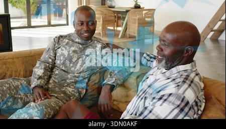 Sprechender Camouflage-Uniform-Soldat und Mann in kariertem Hemd plaudern auf Sofa in der Nähe von Fenstern zu Hause Stockfoto