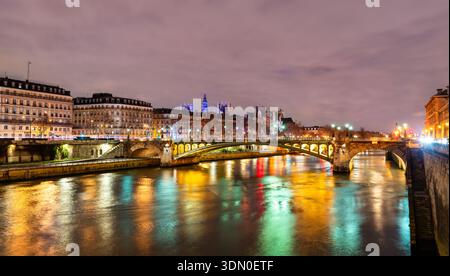 Die Brücke Pont Notre-Dame überquert die seine mit farbenfrohen Lichtreflexen auf dem Wasser am Abend in Paris, Frankreich Stockfoto
