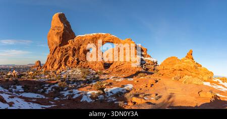 Dieses Panorama bei Sonnenaufgang im Winter bietet sanftes Morgenlicht, das den Turret Arch im Arches National Park in Moab, Utah, beleuchtet. Stockfoto