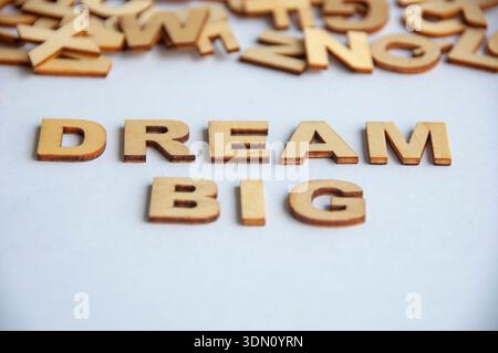 Großer Text aus Holzbuchstaben auf weißem Hintergrund, der Ehrgeiz, Motivation und persönliches Wachstumskonzept symbolisiert. Stockfoto