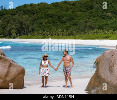 Ein paar Spaziergänge Hand in Hand entlang der unberührten Küste von Anse Cocos Beach, La Digue, Seychellen. Stockfoto