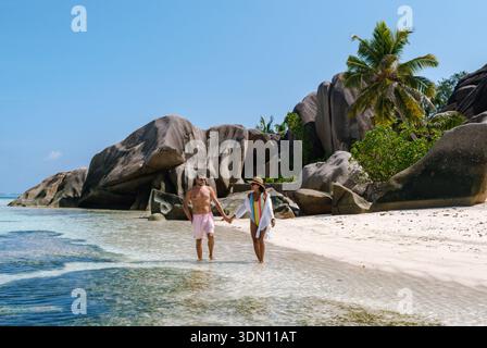 Ein paar Spaziergänge Hand in Hand entlang der atemberaubenden Küste des Anse Source d'Argent Strandes in La Digue, Seychellen. Stockfoto