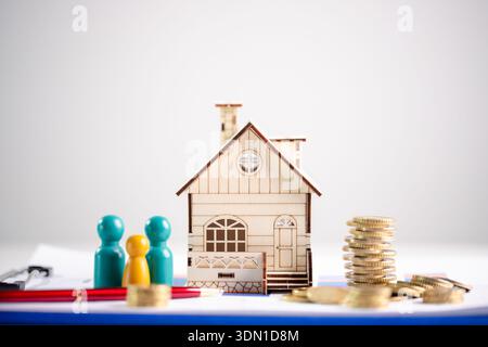 Hauseigentumsplanung und Haushaltsbudgetkonzept für Hypotheken und Sparguthaben, mit Miniatur-Holzhaus mit Münzstapeln, farbenfroher familienanlage Stockfoto