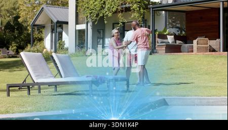 Begrüßung einer Seniorin und zwei Männer in legeren Sommerkleidung, die sich auf dem Rasen am Pool umarmen Stockfoto