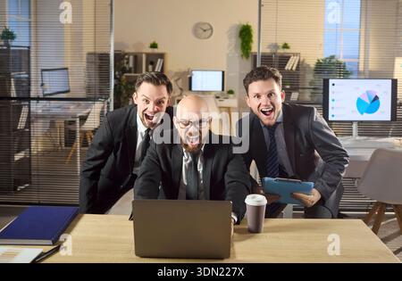 Das aufregende Business-Team jubelt den Laptop an und feiert den Sieg im Büro Stockfoto