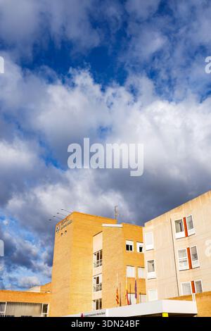 Ein flaches Bild der Fassade aus Ziegelstein und Stein des Krankenhauses mit den offiziellen Schildern und regionalen Flaggen vor dem Hintergrund des leuchtend blauen Himmels Stockfoto