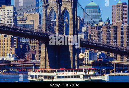 USA, New York City, Brooklyn Bridge mit einem Circle Line Sightseeing Cruises Boot auf dem East River im Vordergrund. Stockfoto