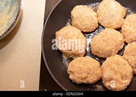 Panierte rohe Hähnchenkoteletts in der Pfanne während des Kochprozesses zu Hause braten Stockfoto