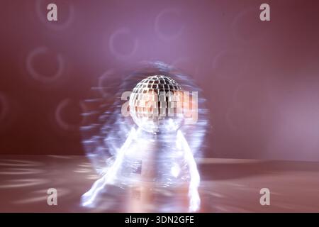 Lichteffekte mit einer rotierenden Tangokugel, die mit kleinen Spiegeln bedeckt ist. Sorgen Sie für Reflexionen und Bewegungsunschärfen. Helle Malerei. Stockfoto