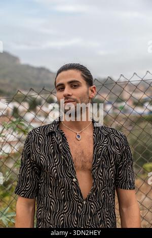 Junger selbstbewusster Mann mit Halskette und stilvollem Hemd Stockfoto