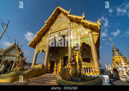 Dok kham Tai, Phayao, Thailand - 8. Februar 2026: Wat Don Chai, eine aufwendig verzierte Tempelfassade mit goldenen Nagagaskulpturen und verzierten c Stockfoto