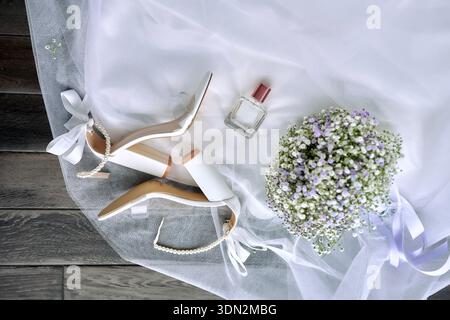 Elegante Hochzeit Flat Lay mit Parfümflasche, weißen Schuhen und Blumen auf weißem Stoff Stockfoto