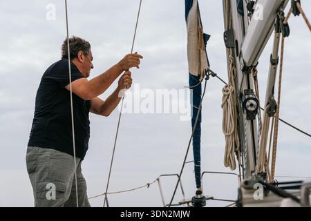 Seemann zieht Seile auf einem Segelboot, das sich auf die Reise vorbereitet Stockfoto