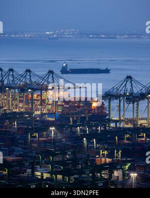 Blick auf den Hafen von Singapur in der Abenddämmerung mit Frachtschiffen, Containern und Kränen am Pasir Panjang Terminal Stockfoto