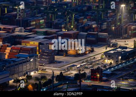 Blick auf den Hafen von Singapur in der Abenddämmerung mit Frachtschiffen, Containern und Kränen am Pasir Panjang Terminal Stockfoto