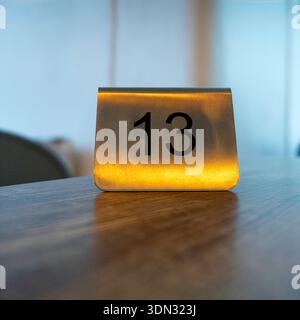 Der Tisch Nr. 13 wird von warmem Licht beleuchtet und ist ideal für Restaurants, Cafés, Bars oder Gastfreundschaften. Stockfoto