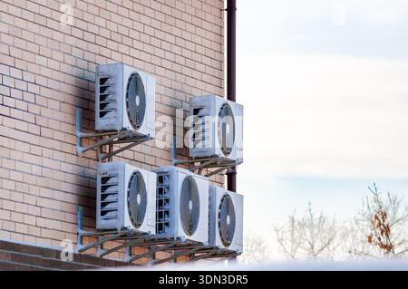 Mehrere Klimaanlagen sind an der Außenwand eines Ziegelgebäudes montiert und zeigen Anzeichen von Winter und Schnee darauf. Stockfoto