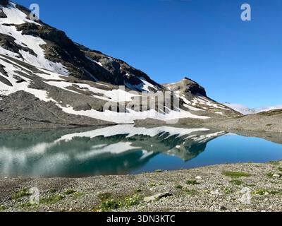 Malerischer Bergsee Rawilseeli bei Lenk im Berner Oberland, der schneebedeckte Schweizer Berge in ruhigem, kristallklarem Wasser reflektiert. Stockfoto