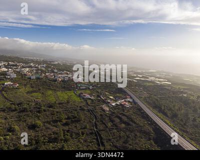Aus der Vogelperspektive auf die kurvenreiche Autobahn, die durch sonnenverwöhnte Landschaften und raues Gelände führt, El Teide, Teneriffa, Spanien. Stockfoto