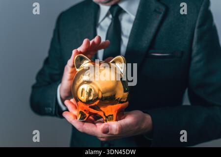 Geschäftsmann mit goldener Sparkasse, Sparkonzept und Anlagekonzept, selektiver Fokus Stockfoto