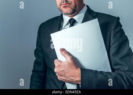 Geschäftsmann in Anzug mit leerem Dokumentenordner, der Geschäftsunterlagen, Vertraulichkeit, Unternehmensverantwortung und professionelles Management repräsentiert Stockfoto