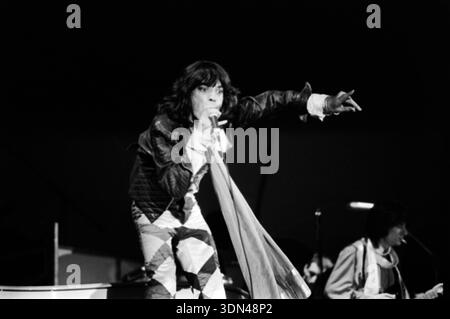 Mick Jagger tritt 1976 mit den Rolling Stones bei einem Konzert im Zuiderpark in den Haag auf. Das dynamische Schwarz-weiß-Foto fängt Jagger mitten im Lied ein und gibt dem Publikum Gesten, während Ron Wood im Hintergrund leicht sichtbar ist. Stockfoto