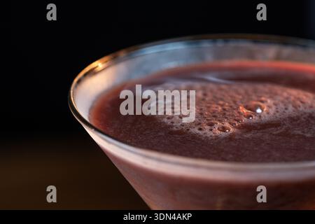 Nahaufnahme eines Schokoladen-Martinis, der in ein gekühltes Glas mit einem stimmungsvollen Hintergrund gegossen wird. Stockfoto