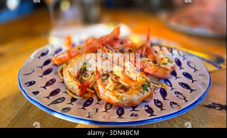 Appetitliche italienische Spaghetti auf einem dekorativen Teller mit Wildfanggarnelen, dazu frische Petersilie, Knoblauch und Olivenöl. Stockfoto