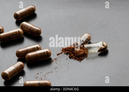 Kapsel mit braunem Pulver auf schwarzem Hintergrund zum Thema Medikamente, Nahrungsergänzungsmittel, Behandlung und Vitamine Stockfoto