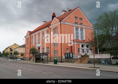 Ein großes rotes Gebäude in Nynashamn mit weißer Verkleidung befindet sich an einer Straße. Das Gebäude hat viele Fenster und einen Balkon. Stockfoto