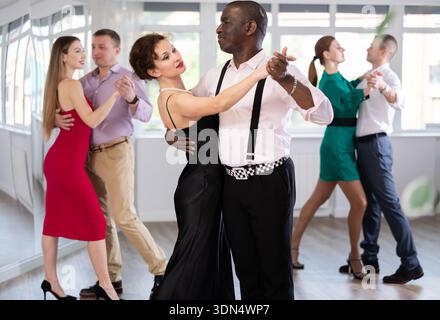 Männer und Frauen verschiedener Nationalitäten tanzen gemeinsam im Tanzstudio Walzer Stockfoto
