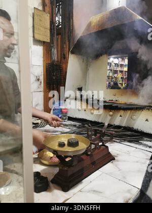 Mann, der Essen in einem Rauchofen in der Medina von Marrakesch, Marokko, zubereitet Stockfoto