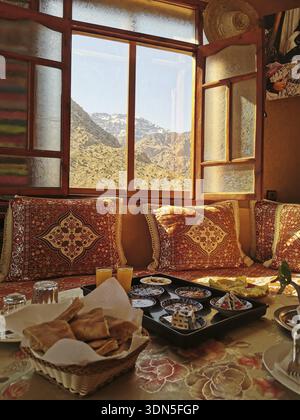 Traditionelles Zimmer mit Bergblick und Frühstück im warmen Licht des morgens, Atlasgebirge, Marokko Stockfoto