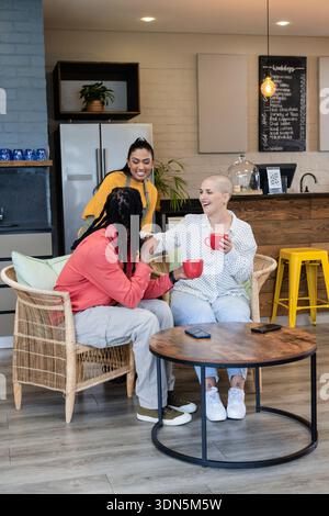 Verschiedene Kollegen plaudern und trinken Kaffee mit roten Tassen in der Lounge am Kühlschrank, QR-Code-Schild Stockfoto